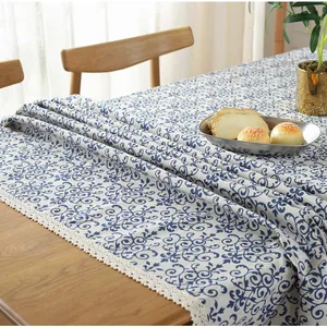 Nappe en lin avec volutes bleues et bordure en dentelle blanche sur table bois