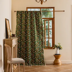 Detail van groen bohemien gordijn met bloemenprint en witte pomponrand aan roede