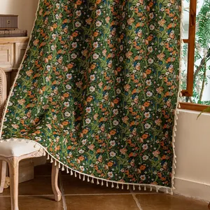 Detail van rode jacquard gordijnen met vintage bloemenprints en crème kwastjes aan de rand