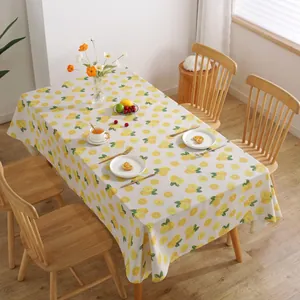 Detail van katoen-linnen tafelkleed met citroenpatronen op een rustieke houten eettafel