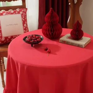 Close-up of red round linen tablecloth with elegant ruffled lace hem and woven texture