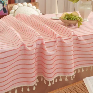 Detail van roze-wit gestreept tafelkleed met crèmekleurige kwastjesranden en katoentextuur