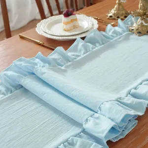 Detail van babyblauwe tafelloper met getextureerde stof en delicate ruchesrand