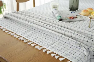 Detailed view of Nordic blue checkered cotton linen tablecloth with white fringe trim