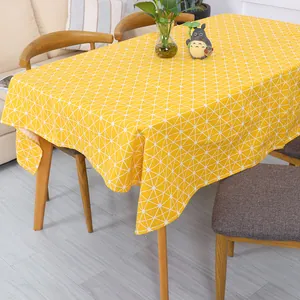 Detail van het gele tafelkleed met witte geometrische patronen op een houten eettafel