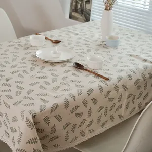 Détail de nappe en lin avec motifs de feuilles vertes et bordure en dentelle