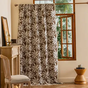 Detail van boho gordijn met palmbladprint en katoenen kwastjes aan houten raamkozijn