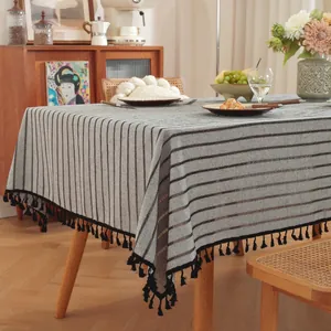 Noords gestreept linnen tafelkleed met zwarte kwastjes op een houten eettafel in huiselijke sfeer