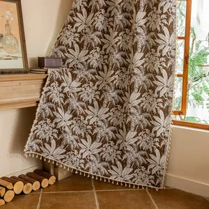 Detail van retro bruin gordijn met palmbladprint en elegante crèmekleurige kwastjes