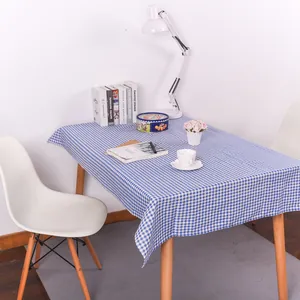 Detail van blauw en wit geblokt linnen tafelkleed met natuurlijke val op houten tafel