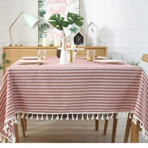 Detail van rood en wit gestreept tafelkleed met dikke witte katoenen kwastjes op hout
