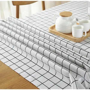 Detailopname van zwart-wit geblokt linnen tafelkleed textuur op een houten eettafel