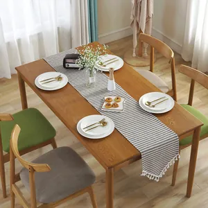 Detail of grey striped cotton linen table runner with elegant white fringe tassels