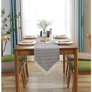 Detailed view of grey and white striped linen table runner with elegant white tassels