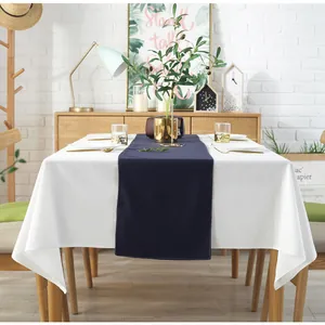 Minimalistisch wit geplooid katoenen tafelkleed met donkerblauwe loper voor decoratie