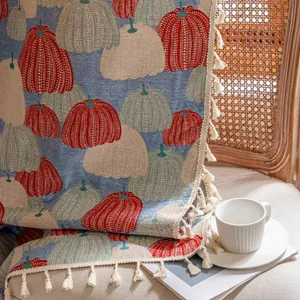 Detail van een boho geweven deken met pompoenpatronen en witte decoratieve kwastjes