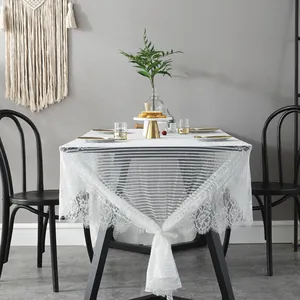 White Nordic lace tablecloth with fringe edge on a black dining table in a home setting