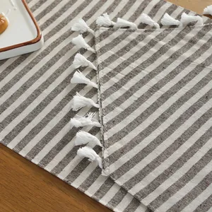 Close-up of striped cotton linen table runner featuring white fringe on wooden surface