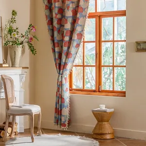 Detail van blauw gordijn met pompoenpatroon en witte bolvormige franjes