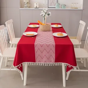 Dettaglio di tovaglia in lino rosso con motivo geometrico bianco ed eleganti frange ai bordi