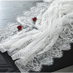 White eyelash lace tablecloth with floral patterns on a dark wood background
