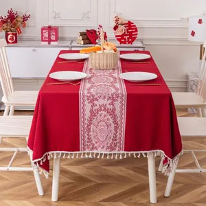 Dettaglio della tovaglia festiva rossa con motivi jacquard bianchi e bordo con frange