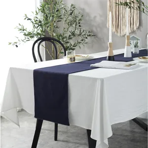 Detail van de marineblauwe katoen-linnen tafelloper met wit stiksel op een houten tafel