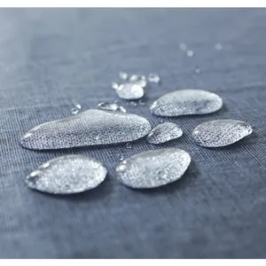 Vista macro di una tovaglia di lino impermeabile con gocce d'acqua sul tessuto grigio
