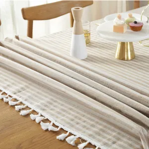 Detail van gestreepte tafelloper met witte kwastjes op een houten eettafel setting