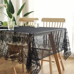 Close-up of black floral lace tablecloth with elegant eyelash fringe on wood table
