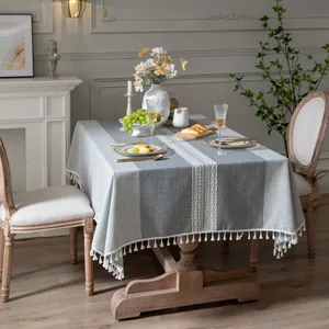 Dettaglio di tovaglia in lino grigio con nappe bianche e strisce verticali moderne