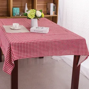 Detail van rood en wit geruit tafelkleed op een donkere houten tafel met boeken