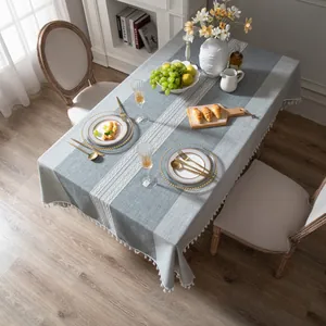 Dettaglio della tovaglia in lino grigio-blu con pizzo bianco e bordi con nappe
