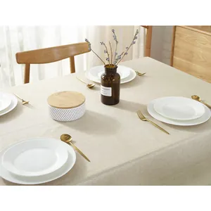 Dettaglio della tovaglia di lino beige impermeabile con piatti e posate d'oro