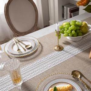 Dettaglio del runner da tavolo in lino beige scuro con ricami geometrici bianchi