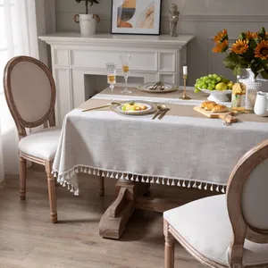 Dettaglio tovaglia in lino grigio con fascia in pizzo bianco e nappe a pompon
