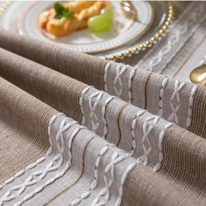 Dettaglio della tovaglia in lino grigio con ricami e frange rustiche per tavola
