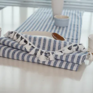 Detail van blauw-wit gestreept katoen-linnen tafelkleed met fijne witte franjes en kwastjes