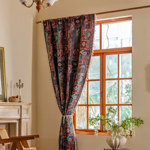 Detail van boheems geometrisch gordijn met kwastjes aan een houten raamkozijn