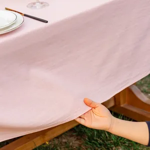 Detail van roze katoenen tafelkleed met stoftextuur en natuurlijke drapering op houten tafel
