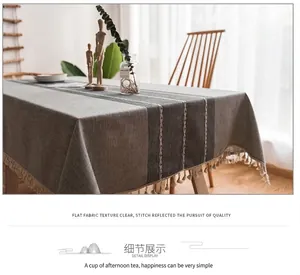Dettaglio tovaglia in lino grigio con strisce scure ed eleganti bordi con nappe crema