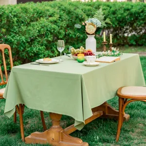 Detailopname van het saliegroene katoenen tafelkleed met textuur op een houten tafel
