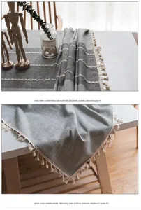 Macro del runner da tavola in lino grigio con ricamo bianco ed eleganti bordi con frange