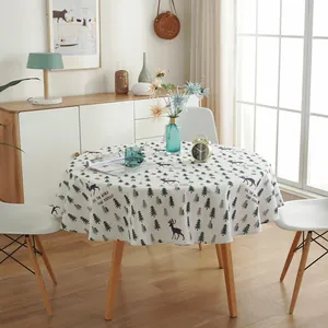 Detail of round nordic tablecloth with green pine tree and reindeer pattern