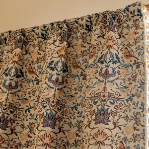 Detail van een vintage gordijn met bloemen- en vogelpatronen en decoratieve kwastjesranden
