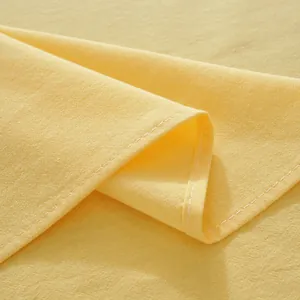Macro shot of light yellow cotton tablecloth fabric with fine texture and white stitching