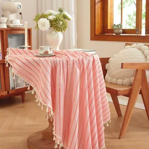 Detail of pink and white striped cotton linen tablecloth with elegant white fringe tassels