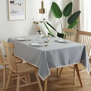 Detail van grijs waterdicht tafelkleed met elegante witte golvende kanten randen