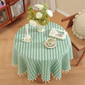 Top view of round green and beige striped tablecloth with cotton tassel edge detail