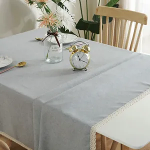 Detail van lichtgrijs linnen tafelkleed met witte kant en decoratieve franjerand